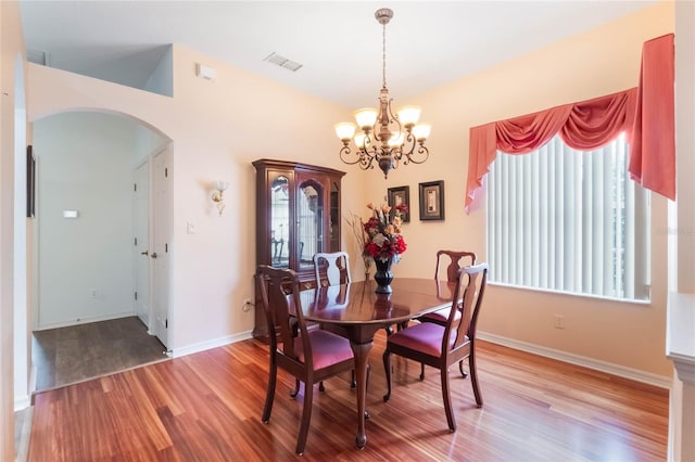 dining room with light wood finished floors, visible vents, arched walkways, baseboards, and a chandelier