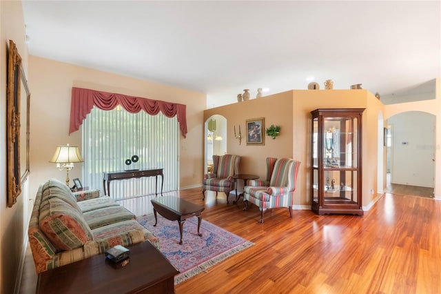 living room with light wood finished floors, baseboards, and arched walkways