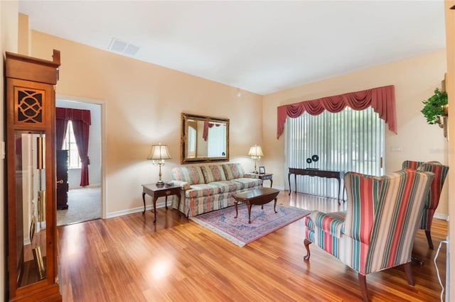 living area with baseboards, visible vents, and wood finished floors