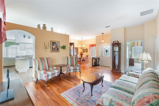 living room with visible vents, light wood-style flooring, and an inviting chandelier