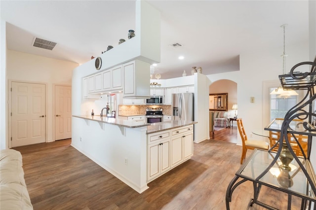 kitchen with visible vents, stainless steel appliances, arched walkways, and wood finished floors