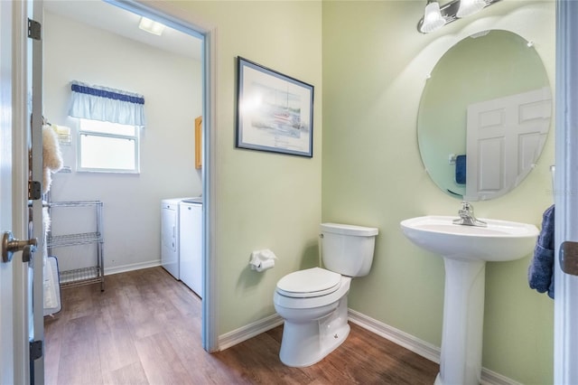 half bath with washing machine and dryer, baseboards, toilet, and wood finished floors