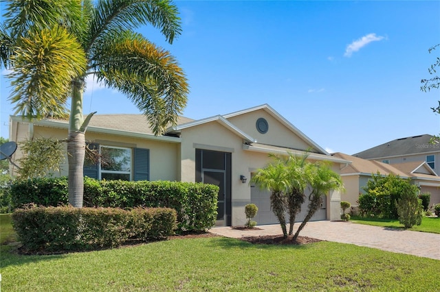 ranch-style house featuring a garage, a front lawn, decorative driveway, and stucco siding