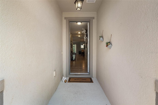 view of exterior entry with visible vents and stucco siding