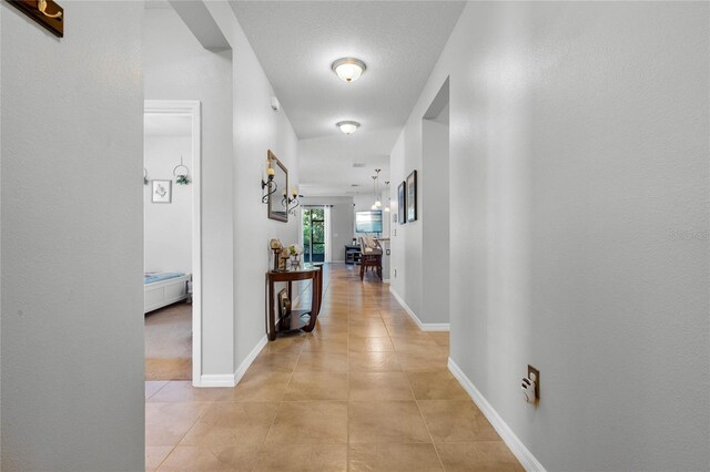 hallway featuring a textured ceiling and light tile patterned floors