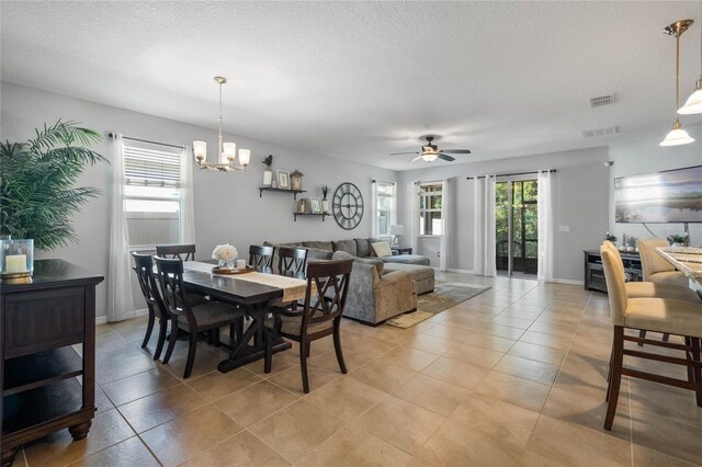 dining room with light tile patterned floors, ceiling fan with notable chandelier, and a textured ceiling