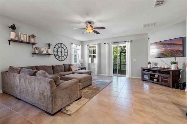 living room featuring ceiling fan, a textured ceiling, and light tile patterned floors