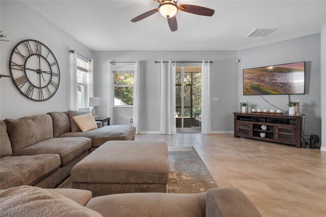 living room with a textured ceiling, light tile patterned floors, and ceiling fan