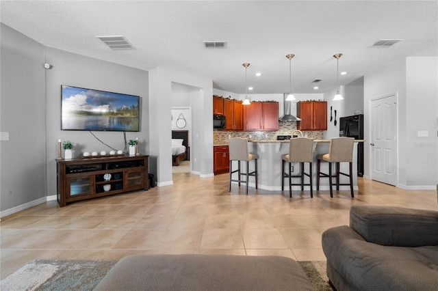 living area featuring light tile patterned flooring, visible vents, and baseboards