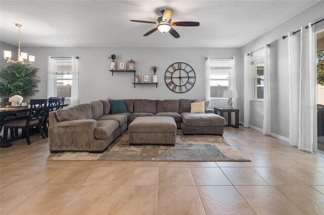 living room with light tile patterned flooring, ceiling fan with notable chandelier, and plenty of natural light