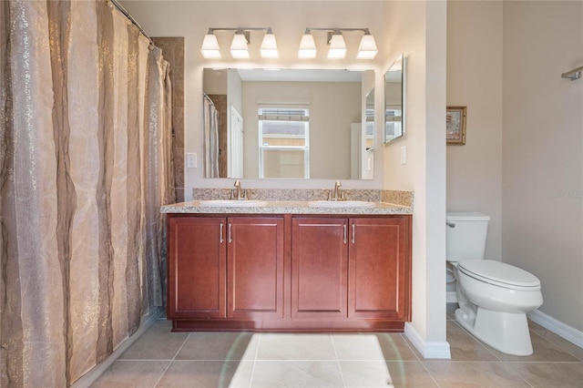 full bath featuring toilet, double vanity, a sink, and tile patterned floors