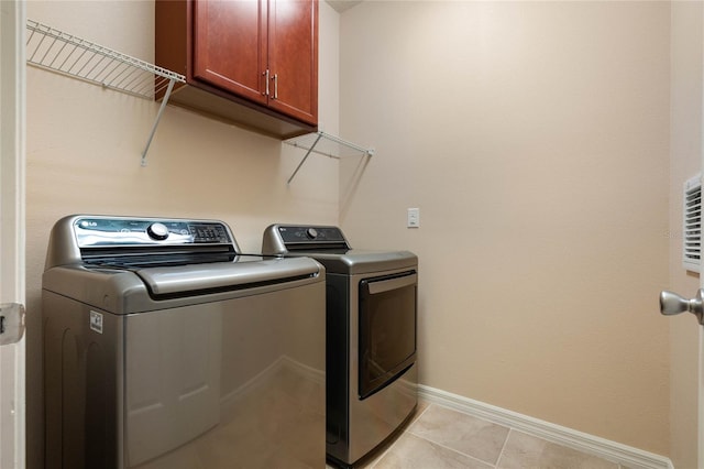 clothes washing area with cabinets, light tile patterned flooring, and separate washer and dryer