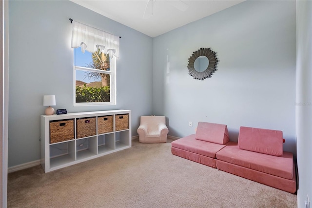 living area featuring carpet floors, ceiling fan, and baseboards