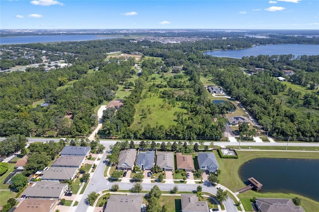 drone / aerial view featuring a water view, a wooded view, and a residential view