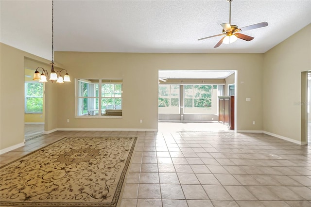 interior space with light tile patterned floors, vaulted ceiling, a textured ceiling, baseboards, and ceiling fan with notable chandelier