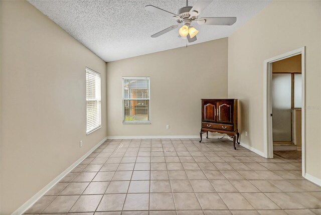 tiled empty room with ceiling fan, lofted ceiling, and a textured ceiling