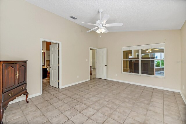 spare room featuring ceiling fan, vaulted ceiling, a textured ceiling, and light tile patterned flooring