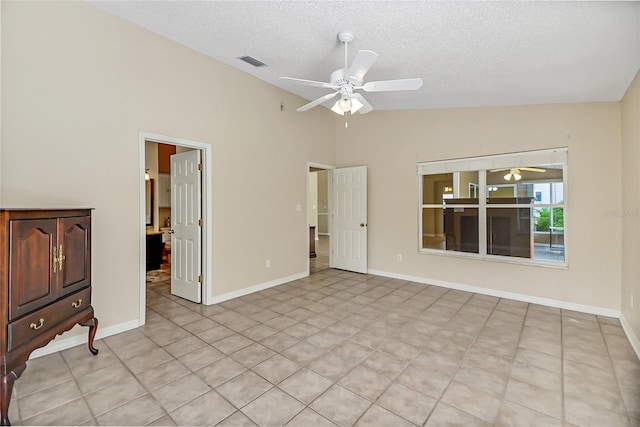 spare room with a ceiling fan, visible vents, vaulted ceiling, and a textured ceiling