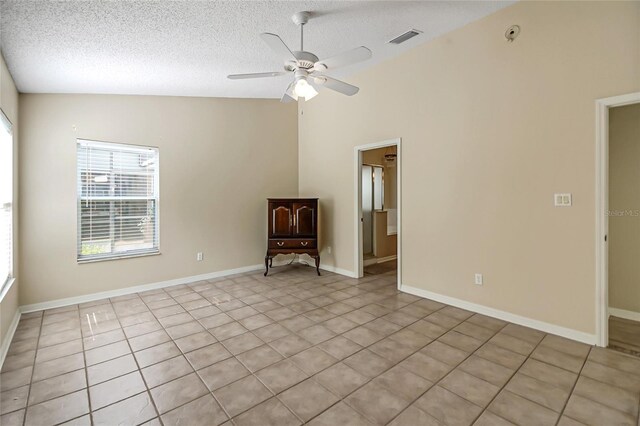 empty room featuring a textured ceiling, high vaulted ceiling, ceiling fan, and light tile patterned flooring