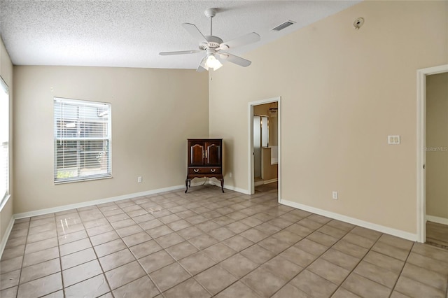 spare room featuring a ceiling fan, lofted ceiling, visible vents, and a textured ceiling