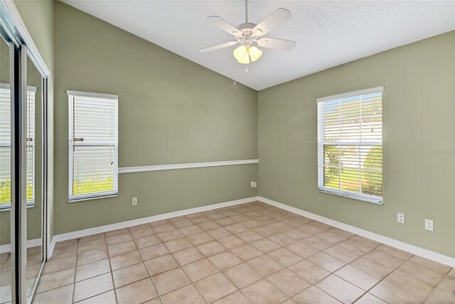 unfurnished room featuring vaulted ceiling, a ceiling fan, and baseboards