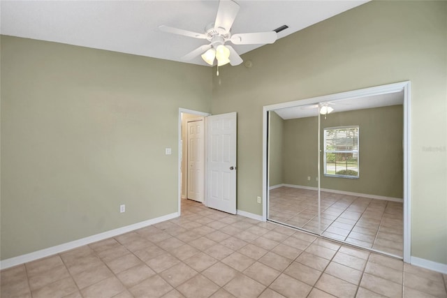 unfurnished bedroom with light tile patterned floors, ceiling fan, baseboards, and a closet