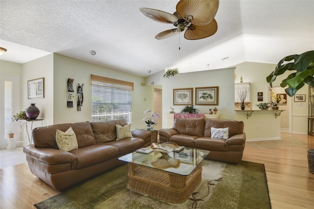 living room featuring a textured ceiling, light hardwood / wood-style flooring, ceiling fan, and vaulted ceiling