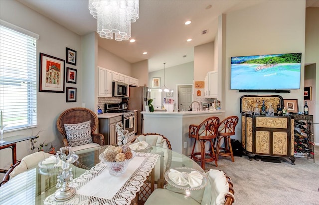 carpeted dining room featuring vaulted ceiling, sink, and a notable chandelier