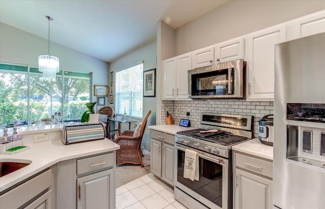 kitchen featuring tasteful backsplash, light carpet, stainless steel appliances, pendant lighting, and lofted ceiling