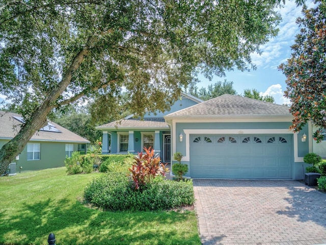 ranch-style home featuring a front lawn, central air condition unit, and a garage