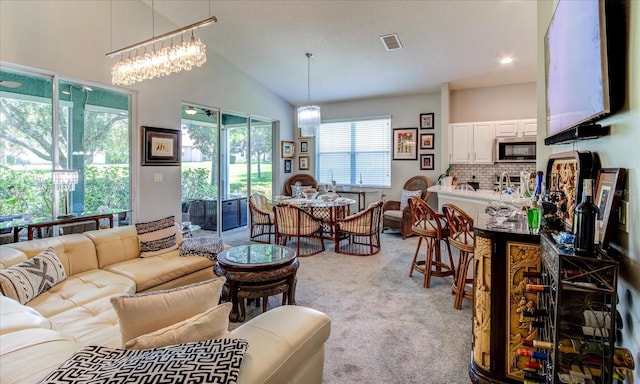 carpeted living room with vaulted ceiling and an inviting chandelier