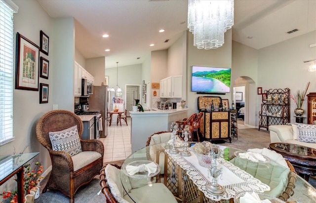 living room with light tile patterned floors, a towering ceiling, an inviting chandelier, and plenty of natural light