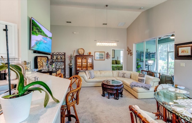 living room featuring carpet flooring, high vaulted ceiling, and a notable chandelier