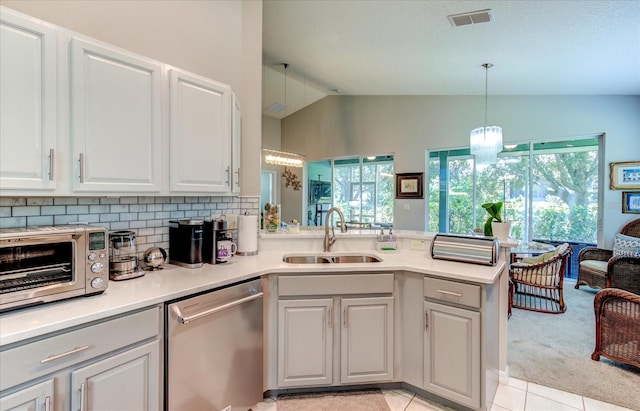 kitchen featuring light tile patterned flooring, vaulted ceiling, kitchen peninsula, and dishwasher