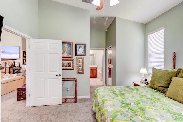 bedroom with ceiling fan, light carpet, ensuite bathroom, and high vaulted ceiling