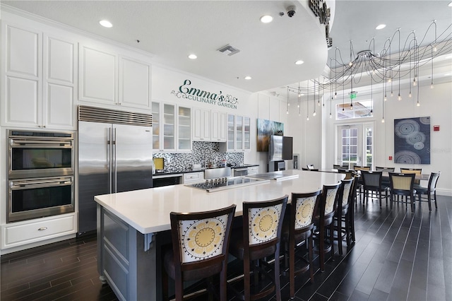 kitchen featuring a kitchen island, stainless steel appliances, white cabinetry, and dark hardwood / wood-style floors