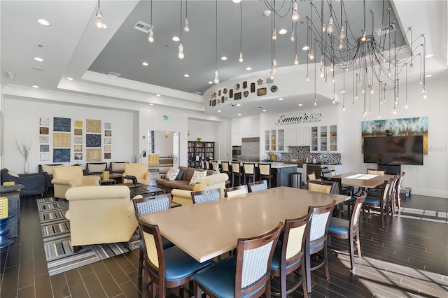 dining space with a towering ceiling, a tray ceiling, dark hardwood / wood-style floors, and a chandelier