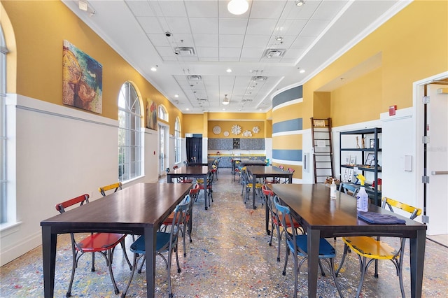 dining space featuring a towering ceiling, ornamental molding, and a drop ceiling