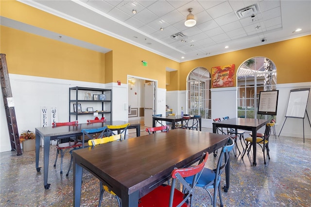 dining space with a towering ceiling and a drop ceiling