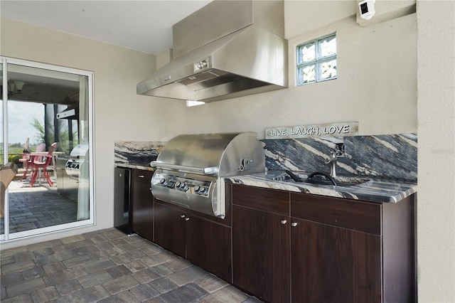 kitchen featuring wall chimney exhaust hood, dark tile patterned floors, fridge, and dark brown cabinets