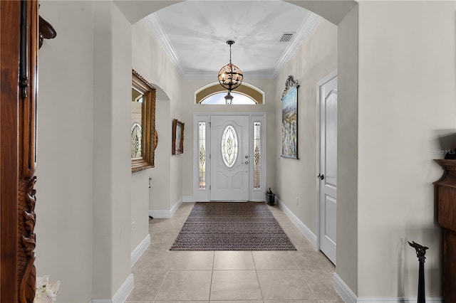 foyer entrance with an inviting chandelier, crown molding, and light tile patterned floors