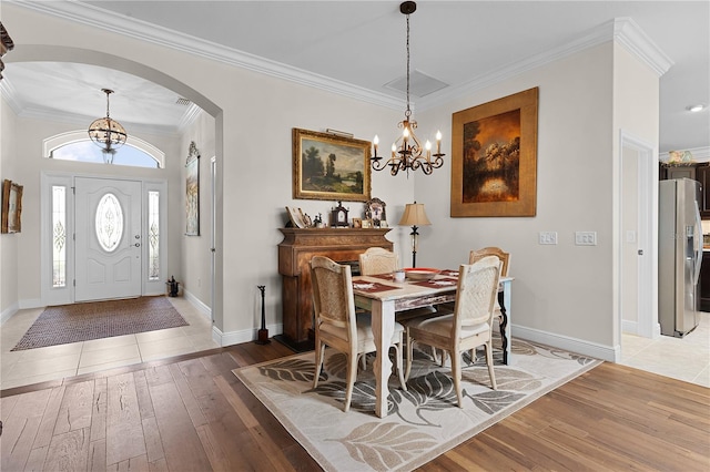 tiled dining space featuring ornamental molding and an inviting chandelier