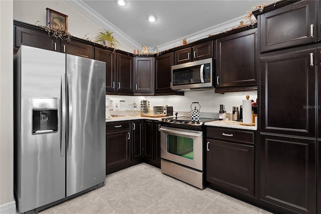 kitchen with light tile patterned flooring, ornamental molding, appliances with stainless steel finishes, dark brown cabinetry, and vaulted ceiling