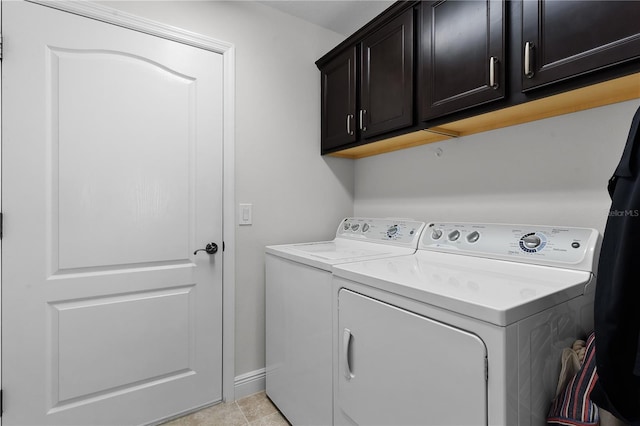 clothes washing area with washer and clothes dryer, light tile patterned floors, and cabinets