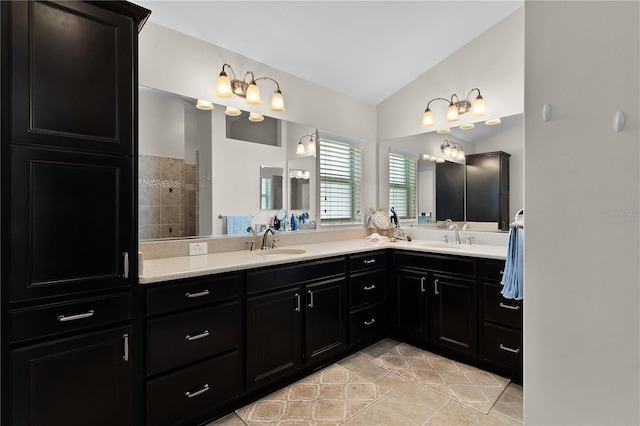 bathroom featuring dual bowl vanity, tile patterned floors, and lofted ceiling