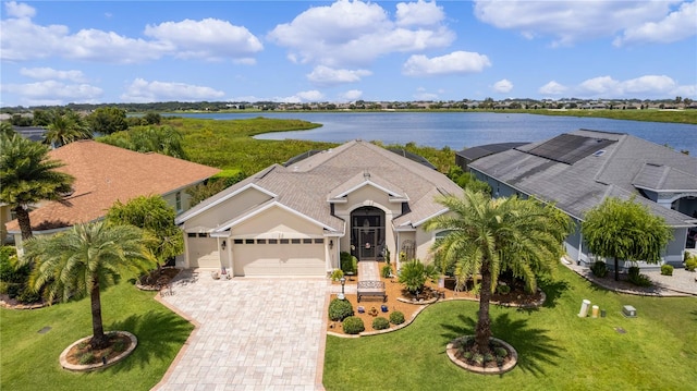 view of front of house featuring a garage, a front lawn, and a water view