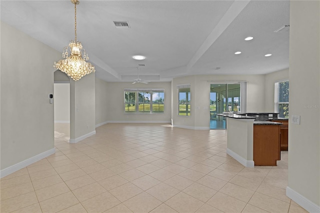 kitchen featuring ceiling fan with notable chandelier, a raised ceiling, light tile patterned floors, and decorative light fixtures