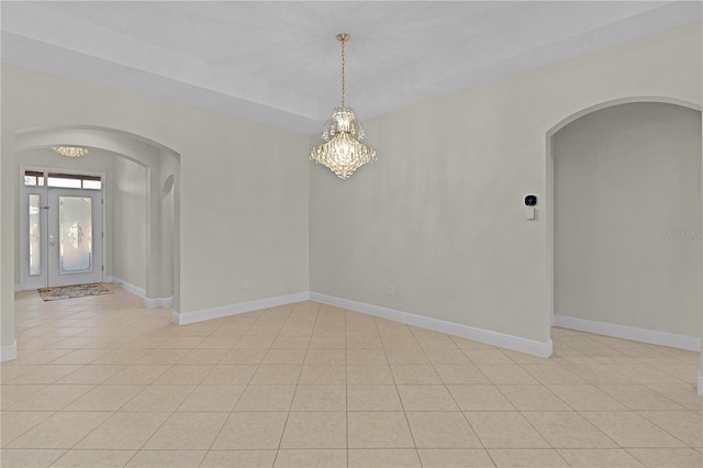 tiled empty room with a notable chandelier