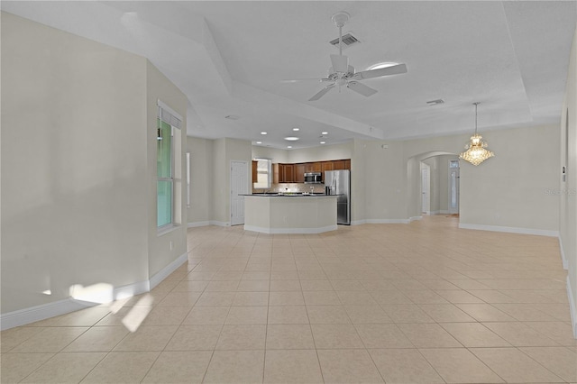 unfurnished living room with ceiling fan, light tile patterned floors, and a tray ceiling