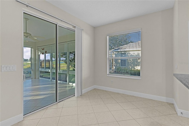 tiled empty room with ceiling fan and a textured ceiling